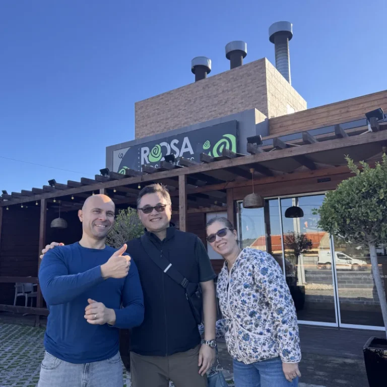 Tiago, dono do restaurante, a receber clientes simpáticos na entrada exterior do Rosa dos Leitões